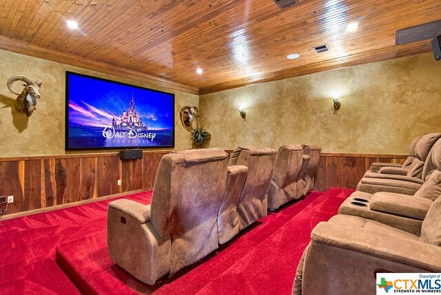 home theater room with carpet floors, wood walls, and wood ceiling