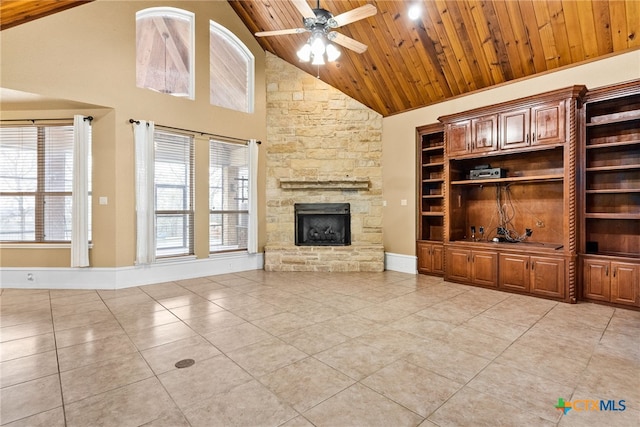 unfurnished living room with light tile patterned floors, a stone fireplace, wood ceiling, and a ceiling fan