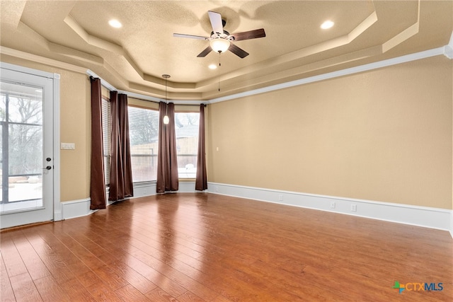 spare room featuring ceiling fan, baseboards, a raised ceiling, and hardwood / wood-style floors