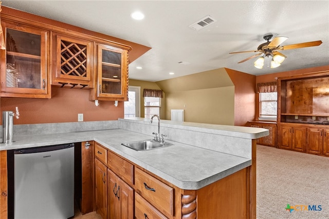 kitchen with a peninsula, a sink, light countertops, dishwasher, and glass insert cabinets