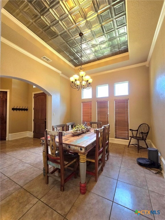 dining area featuring tile patterned flooring, crown molding, and an inviting chandelier