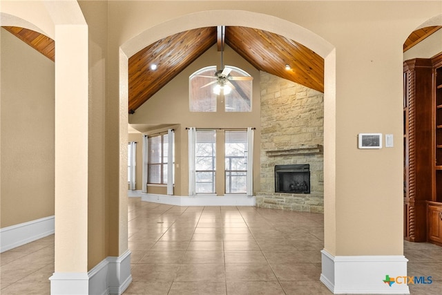unfurnished living room with high vaulted ceiling, wood ceiling, a fireplace, and light tile patterned floors