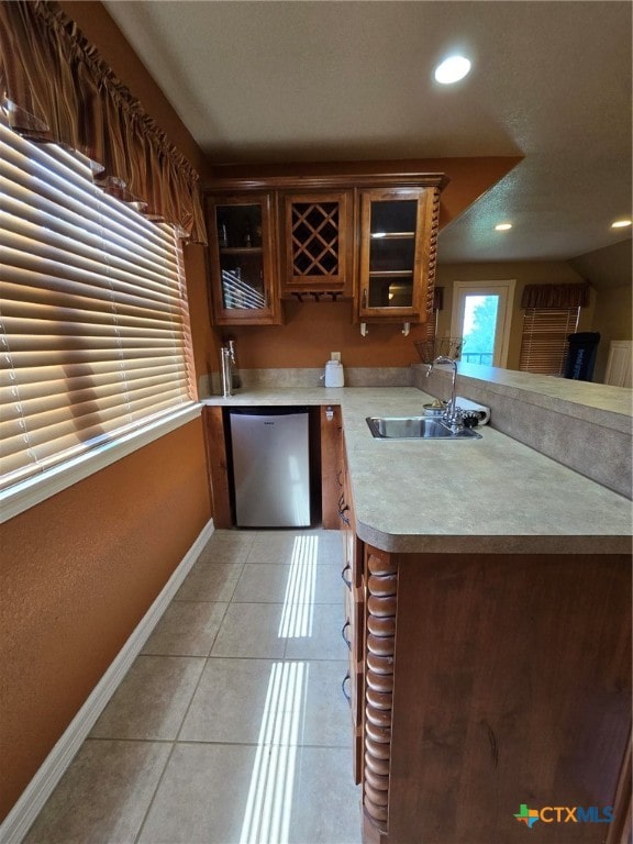 kitchen featuring dishwasher, kitchen peninsula, sink, and light tile patterned floors