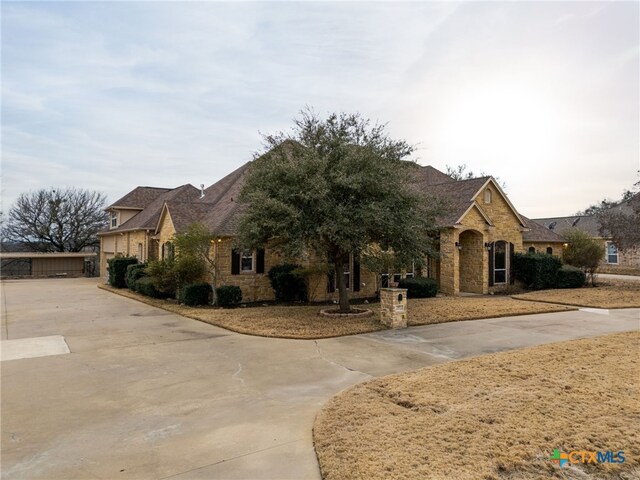 french country style house featuring a garage and stone siding