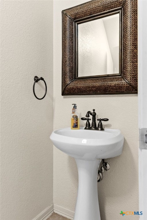 bathroom featuring a textured wall and baseboards