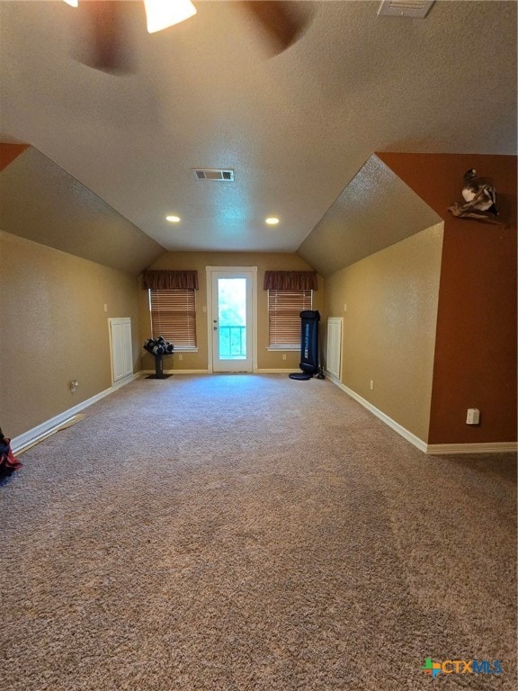 bonus room featuring carpet flooring, lofted ceiling, and a textured ceiling