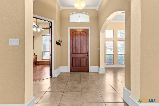 tiled living room featuring built in shelves, ceiling fan, beam ceiling, high vaulted ceiling, and a stone fireplace