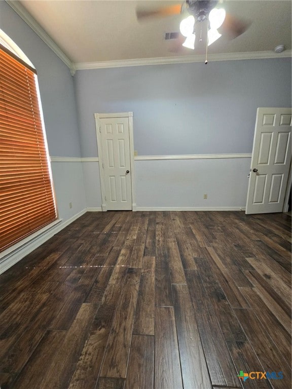 empty room featuring ornamental molding, dark wood-type flooring, and ceiling fan