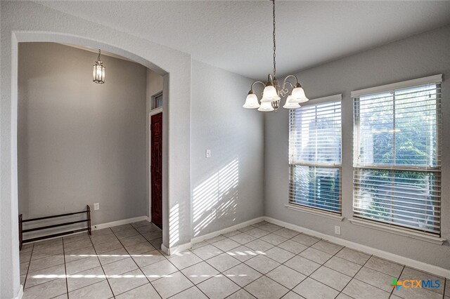 unfurnished dining area featuring a chandelier, a textured ceiling, and light tile patterned floors