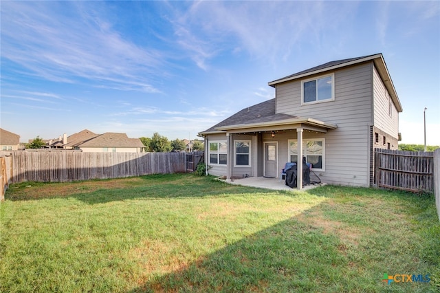 back of property with a yard and a patio area