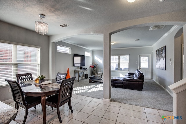 dining room featuring ornamental molding, light colored carpet, a textured ceiling, and an inviting chandelier