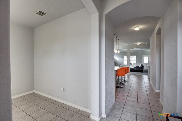 hallway with a textured ceiling and light tile patterned floors