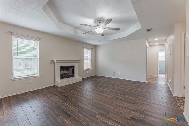 2405 Thoroughbred Dr, Killeen, TX 76549 - unfurnished living room featuring dark wood finished floors, a raised ceiling, baseboards, a brick fireplace, and ceiling fan