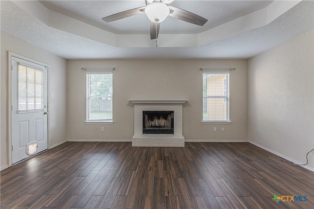 2405 Thoroughbred Dr, Killeen, TX 76549 - unfurnished living room with dark wood finished floors, a brick fireplace, a ceiling fan, and baseboards