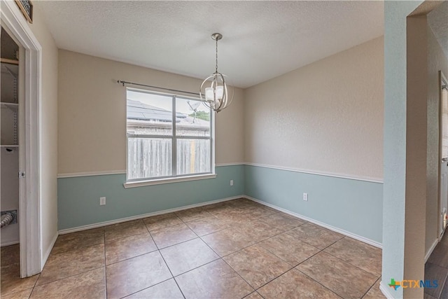 2405 Thoroughbred Dr, Killeen, TX 76549 - unfurnished dining area featuring an inviting chandelier, tile patterned flooring, a textured ceiling, and baseboards