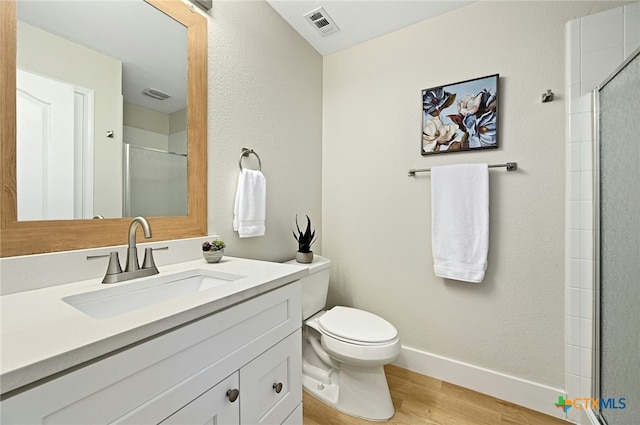 bathroom featuring wood-type flooring, vanity, toilet, and a shower with shower door