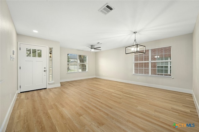 entryway featuring ceiling fan with notable chandelier, a healthy amount of sunlight, and light wood-type flooring