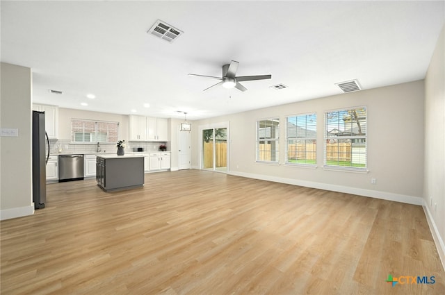 unfurnished living room featuring ceiling fan with notable chandelier, sink, and light hardwood / wood-style flooring