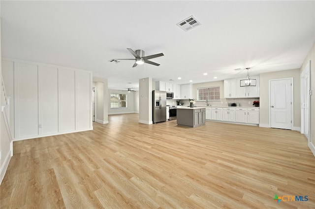 unfurnished living room with sink, light hardwood / wood-style floors, and ceiling fan with notable chandelier