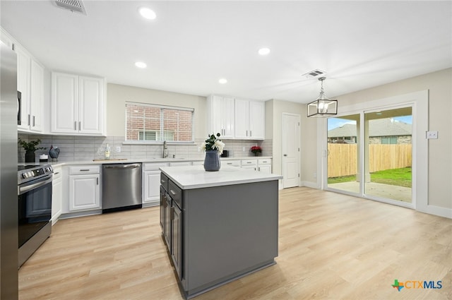 kitchen featuring white cabinetry, an inviting chandelier, pendant lighting, a kitchen island, and appliances with stainless steel finishes