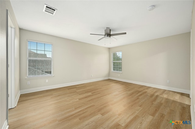 spare room with light wood-type flooring, a wealth of natural light, and ceiling fan