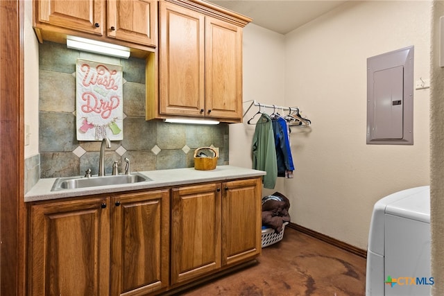 kitchen with backsplash, baseboards, electric panel, washer / dryer, and a sink