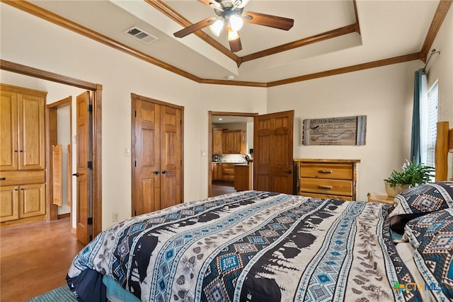 bedroom with visible vents, crown molding, a tray ceiling, a closet, and a ceiling fan