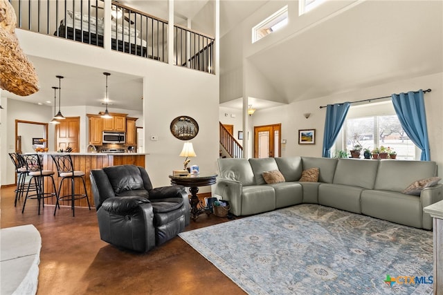 living area with stairs, a towering ceiling, and finished concrete floors