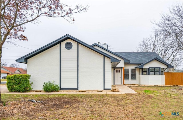 back of property featuring fence, a lawn, and brick siding