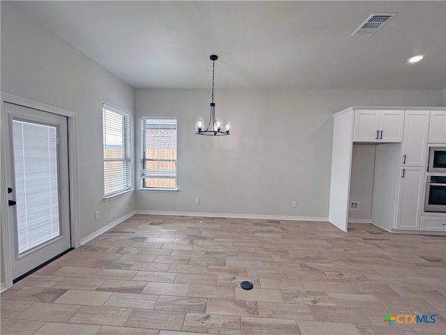 unfurnished dining area featuring a chandelier, light wood-style flooring, visible vents, and baseboards