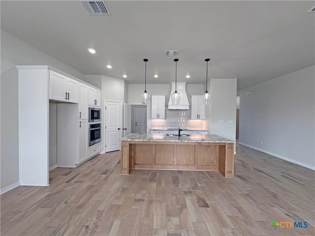 kitchen with stainless steel appliances, visible vents, a sink, and custom exhaust hood