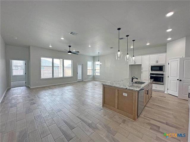 kitchen featuring visible vents, appliances with stainless steel finishes, open floor plan, a sink, and light wood-type flooring