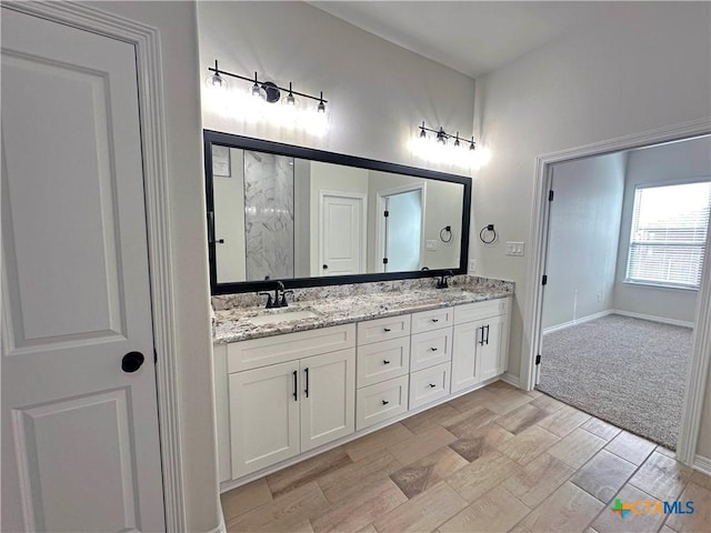 bathroom with a sink, baseboards, and double vanity