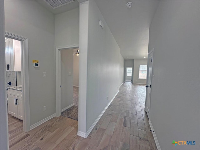 corridor featuring light wood-type flooring, baseboards, and visible vents