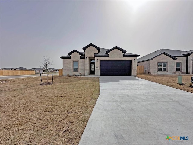 view of front of home with a garage, a front yard, concrete driveway, and fence