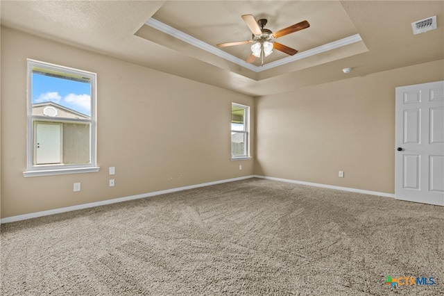 carpeted empty room featuring ceiling fan, ornamental molding, and a tray ceiling