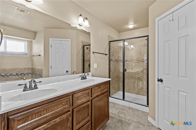 bathroom with vanity, a textured ceiling, and a shower with shower door