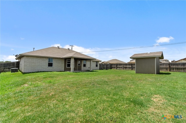 rear view of house with a storage unit and a yard