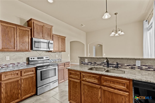 kitchen featuring backsplash, appliances with stainless steel finishes, a notable chandelier, pendant lighting, and sink