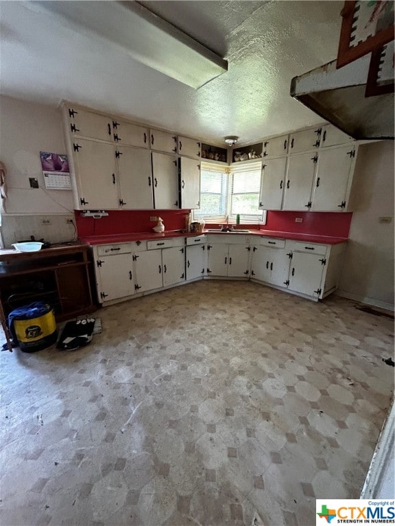 kitchen with white cabinets, a textured ceiling, and sink