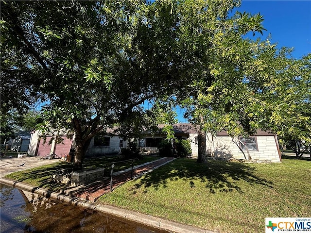 903 N Cherry St, Seguin, TX 78155 - view of property hidden behind natural elements featuring a front lawn, concrete driveway, and a garage