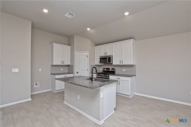 132 Periwinkle Ln, Bastrop, TX 78602 - kitchen featuring visible vents, an island with sink, a sink, backsplash, and appliances with stainless steel finishes