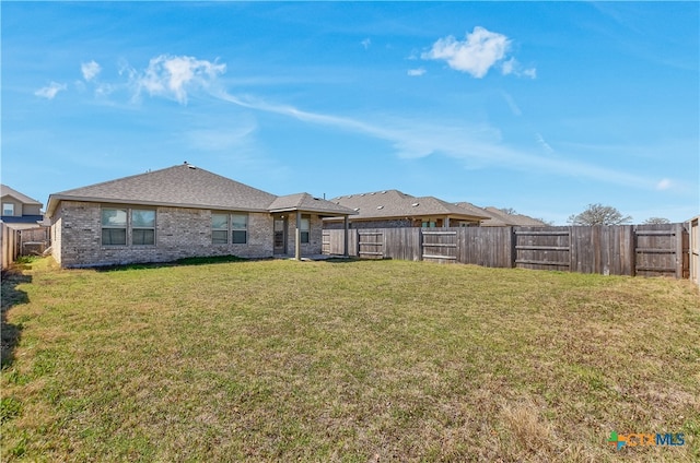 132 Periwinkle Ln, Bastrop, TX 78602 - back of house with a fenced backyard, brick siding, and a yard