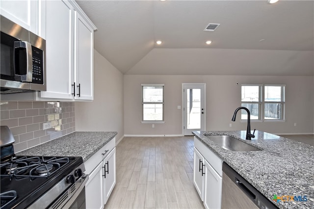132 Periwinkle Ln, Bastrop, TX 78602 - kitchen with a sink, light stone counters, backsplash, appliances with stainless steel finishes, and lofted ceiling