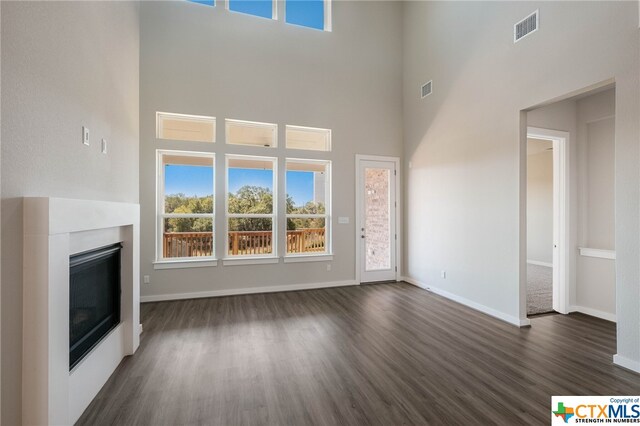 unfurnished living room with a towering ceiling and dark hardwood / wood-style flooring