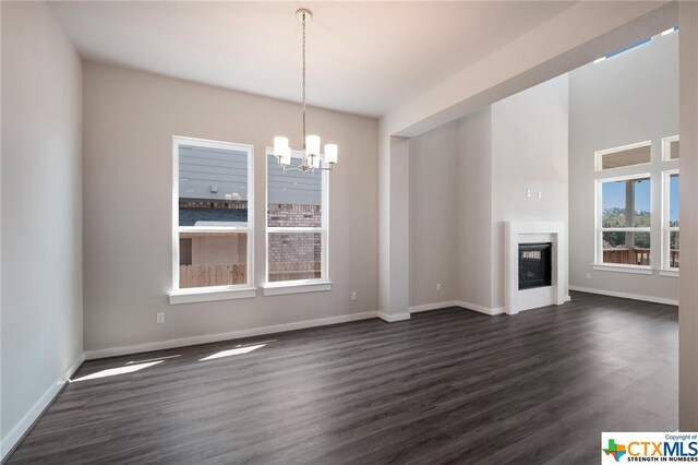 unfurnished living room featuring dark hardwood / wood-style floors and an inviting chandelier