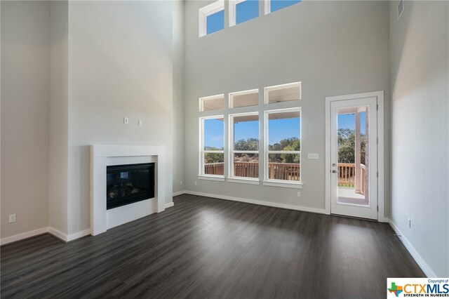 unfurnished living room with a high ceiling and dark hardwood / wood-style flooring