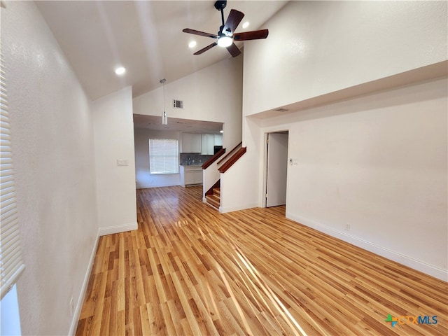 unfurnished living room featuring high vaulted ceiling, ceiling fan, and light hardwood / wood-style floors