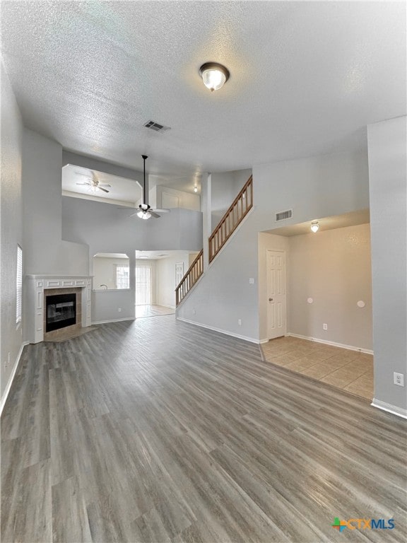 unfurnished living room with a textured ceiling, hardwood / wood-style floors, a fireplace, and ceiling fan