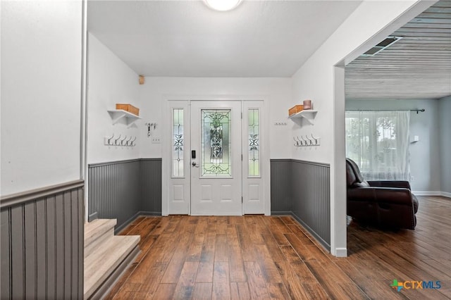 entryway with hardwood / wood-style flooring, stairway, and wainscoting